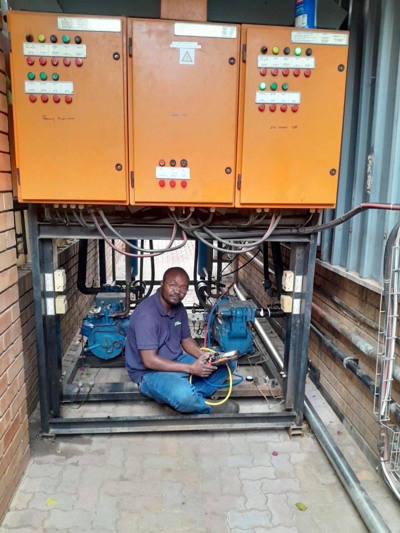 Technician working inside a plant room beneath BMS control panels