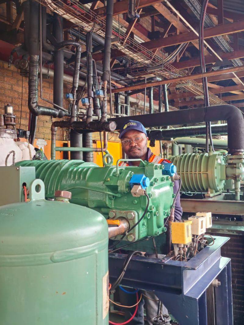 Technician inspecting a compressor inside an industrial plant room