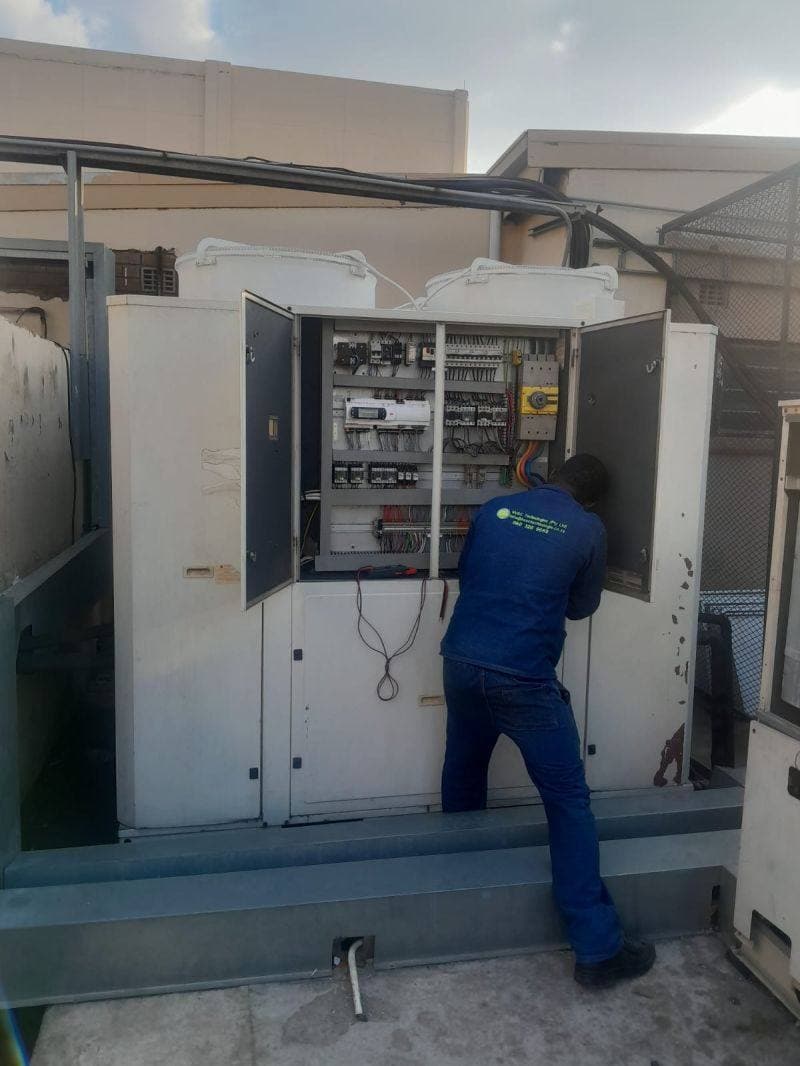HVAC Technologies technician inspecting a rooftop BMS control panel