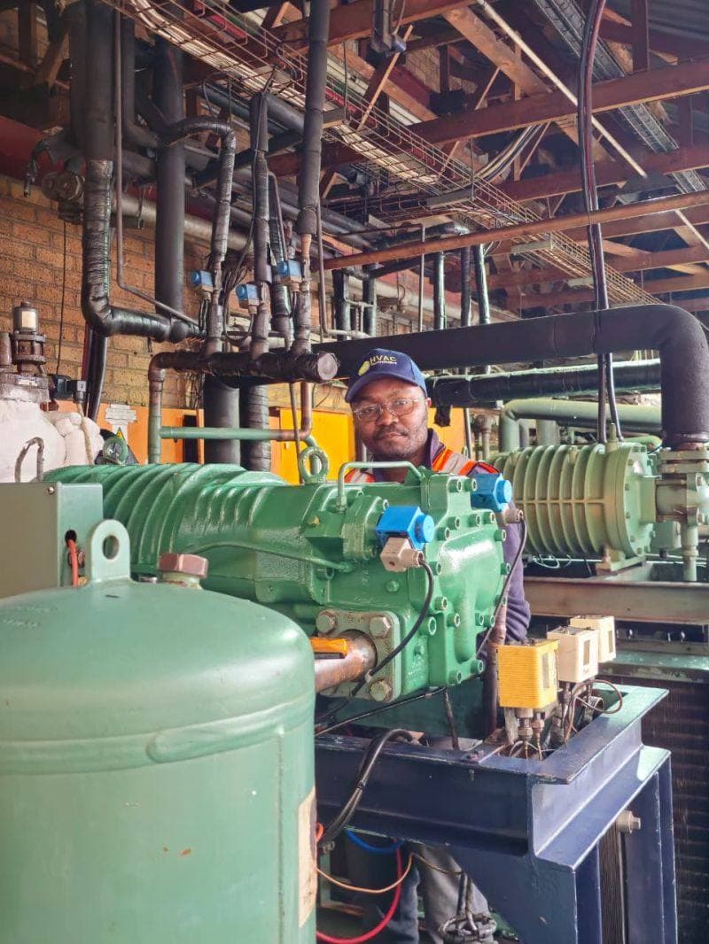 Technician inspecting a compressor inside an industrial plant room
