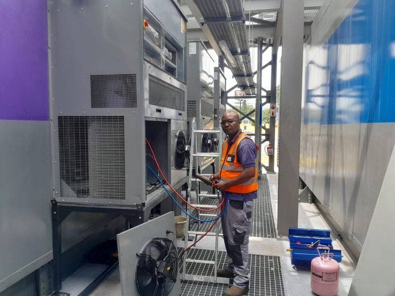 Technician charging refrigerant on a monoblock package unit